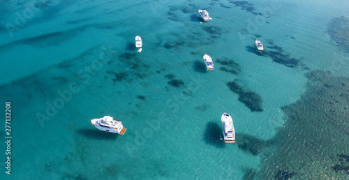 View from above, stunning aerial view of some boats and yachts on a beautiful turquoise clear water. Spiaggia La Pelosa (Pelosa beach) Stintino, Sardinia, Italy.