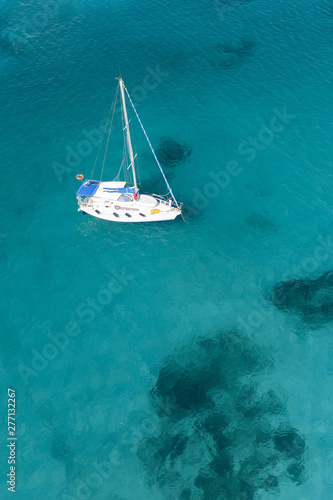 View from above  stunning aerial view of a yacht sailing on a beautiful turquoise clear water. Spiaggia La Pelosa  Pelosa beach  Stintino  Sardinia  Italy.