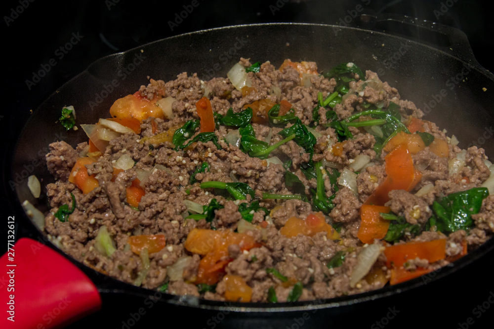 Cast iron skillet cooking ground beef pasta sauce mixture Cast iron skillet cooking ground beef pasta sauce mixture