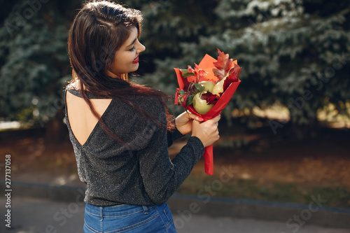 Beautiful girl in a city. Stylish girl in a fashionable clothes. Lady with a unordinary bouquet photo