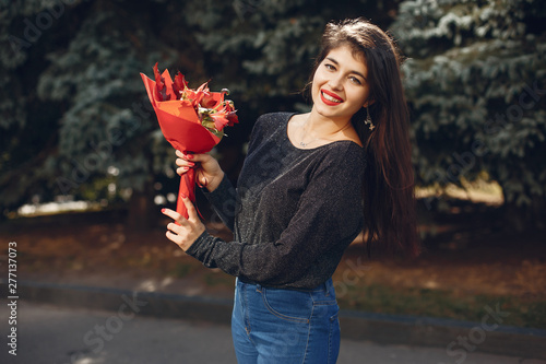 Beautiful girl in a city. Stylish girl in a fashionable clothes. Lady with a unordinary bouquet photo