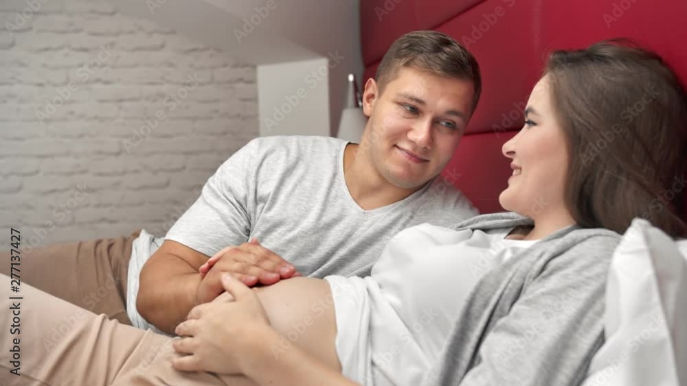 Happy parent future mother and father having tenderness relaxing on bed together Happy parent future mother and father having tenderness relaxing on bed together