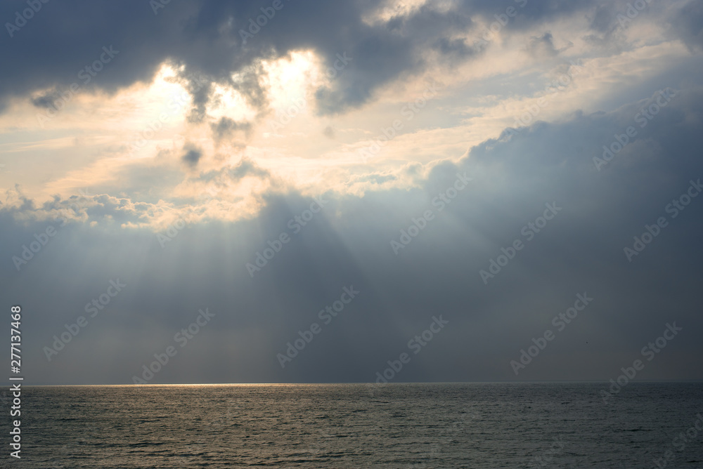 The sea surface in the rays of sunlight on a cloudy day. The sea in the rays of the sun coming through the clouds 