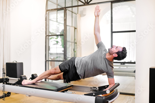 Obraz na płótnie Fit man doing pilates side elbow plank exercises