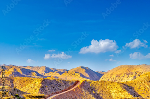 Off-road track through the mountains under a clear blue sky. From Muscat  Oman.