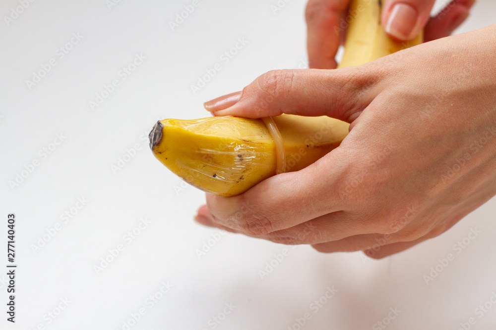 Female hand puts on a condom into a banana. Safety sex concept