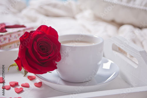 Close up of cup of tea with red rose and small candy hearts on the table