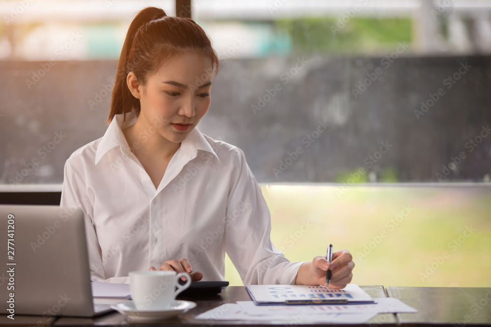 Close up Business women using calculator and writing make note with calculate about cost at home office. Close up Business women using calculator and writing make note with calculate about cost at home office.