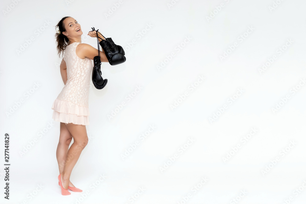 Portrait in full growth on a white background beautiful pretty woman girl in a pink dress, standing with boxing gloves in different poses with different emotions. Smiles Stylish trendy youth. Portrait in full growth on a white background beautiful pretty woman girl in a pink dress, standing with boxing gloves in different poses with different emotions. Smiles Stylish trendy youth.