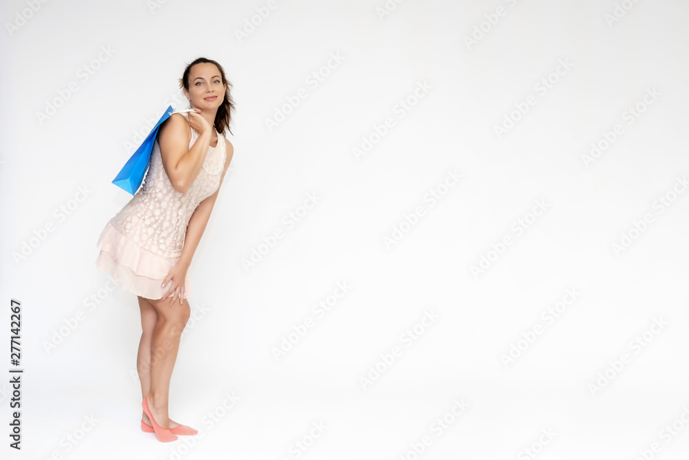 Full-length portrait on white background of a beautiful pretty woman girl in a pink dress, stands with purchases with packages in different poses with different emotions. Smiles Stylish trendy youth.
