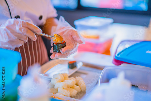Close Up of cook hands preparing japanese food. Japanese cook making sushi at restaurant. Young girl cook serving traditional japanese sushi