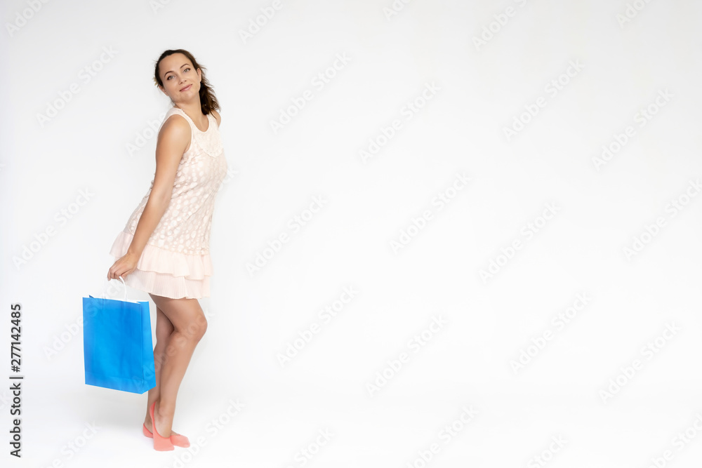 Full-length portrait on white background of a beautiful pretty woman girl in a pink dress, stands with purchases with packages in different poses with different emotions. Smiles Stylish trendy youth. Full-length portrait on white background of a beautiful pretty woman girl in a pink dress, stands with purchases with packages in different poses with different emotions. Smiles Stylish trendy youth.