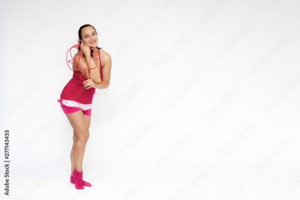 Full-length portrait on white background of beautiful pretty fitness girl woman in pink sport uniform standing exercises in different poses with a skipping rope. Smiles Stylish trendy youth. Full-length portrait on white background of beautiful pretty fitness girl woman in pink sport uniform standing exercises in different poses with a skipping rope. Smiles Stylish trendy youth.
