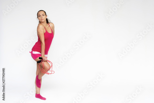 Fototapeta Naklejka Na Ścianę i Meble -  Full-length portrait on white background of beautiful pretty fitness girl woman in pink sport uniform standing exercises in different poses with a skipping rope. Smiles Stylish trendy youth.