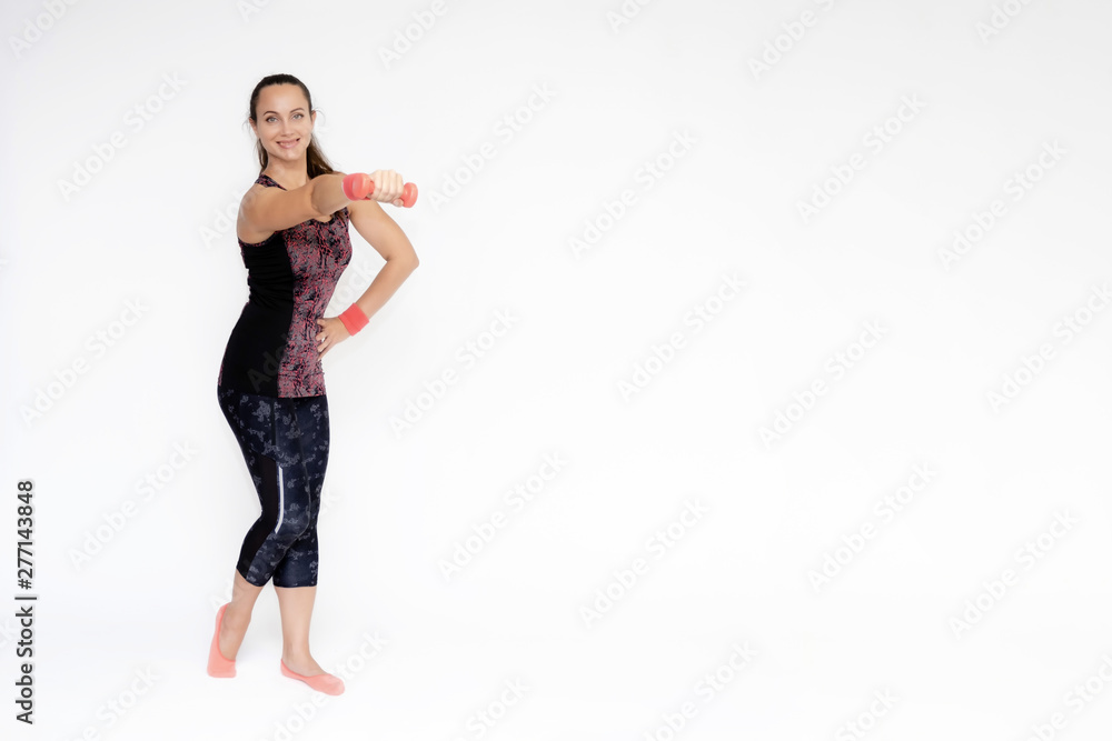 Full-length portrait on white background of beautiful pretty fitness woman girl in fashionable sportswear standing exercising in various poses with dumbbell. Smiles Stylish trendy youth. Full-length portrait on white background of beautiful pretty fitness woman girl in fashionable sportswear standing exercising in various poses with dumbbell. Smiles Stylish trendy youth.