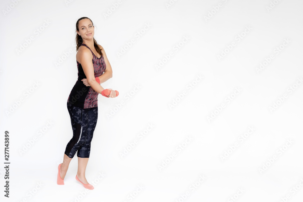 Full-length portrait on white background of beautiful pretty fitness woman girl in fashionable sportswear standing exercising in various poses with dumbbell. Smiles Stylish trendy youth. Full-length portrait on white background of beautiful pretty fitness woman girl in fashionable sportswear standing exercising in various poses with dumbbell. Smiles Stylish trendy youth.