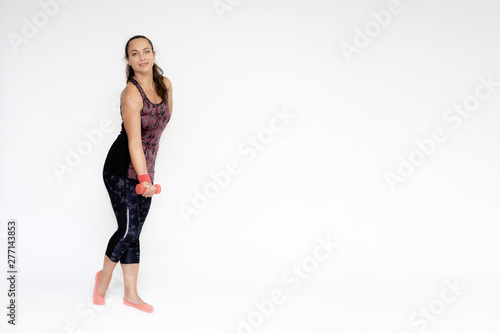 Full-length portrait on white background of beautiful pretty fitness woman girl in fashionable sportswear standing exercising in various poses with dumbbell. Smiles Stylish trendy youth.