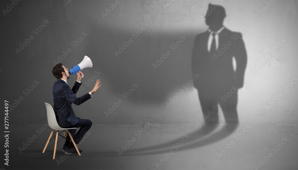 Humble businessman staying and offering stuffs to a huge businessman shadow Humble businessman staying and offering stuffs to a huge businessman shadow
