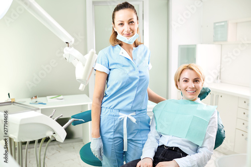 Dentist and patient girl are smiling.