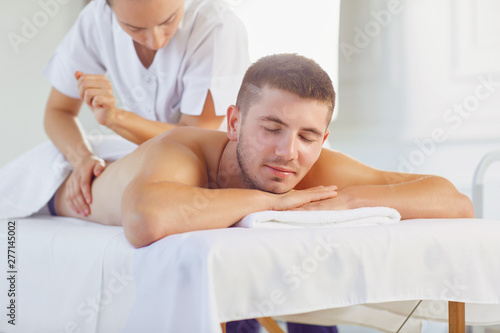 Young man lying on table with eyes closed enjoying massage
