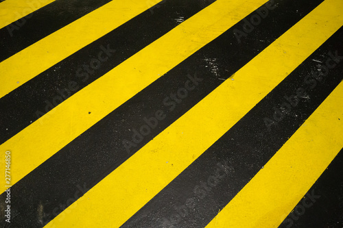 Black and yellow caution warning pattern background on the floor © uppichaya