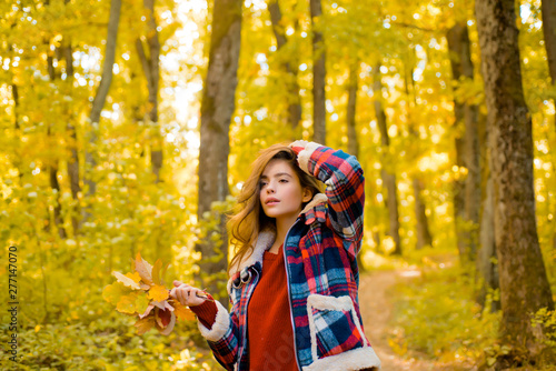 Autumn woman in autumn park with red pullover. Autumn girl. Art work of romantic girl. Warm sunny weather. Autumn outdoor portrait of beautiful happy girl walking in park or forest in warm knitted
