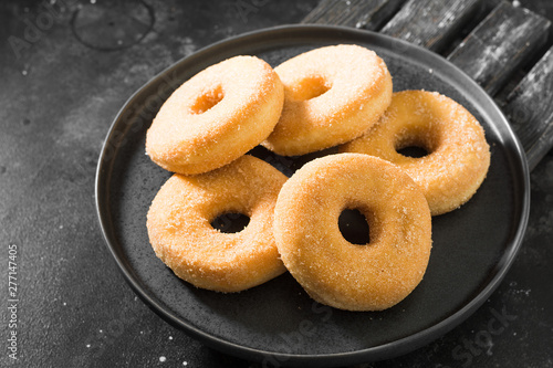 Donuts sprinkled with sugar. Dark background