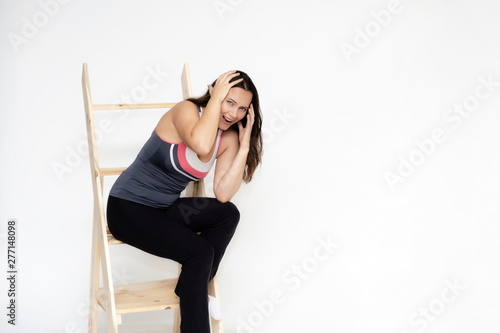 Full-length portrait on white background of beautiful pretty fitness girl woman in sports uniform, sitting on the stairs with different emotions in different poses. Stylish trendy youth.
