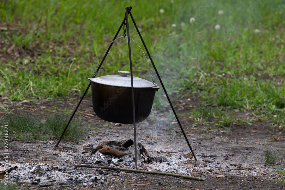 Cooking in field conditions, boiling pot at the campfire on picnic Cooking in field conditions, boiling pot at the campfire on picnic