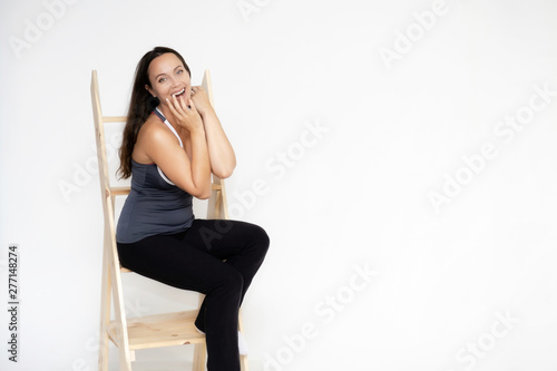 Full-length portrait on white background of beautiful pretty fitness girl woman in sports uniform, sitting on the stairs with different emotions in different poses. Stylish trendy youth.