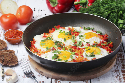 Shakshouka with five cooked eggs on top of tomato sauce in cast iron skillet	