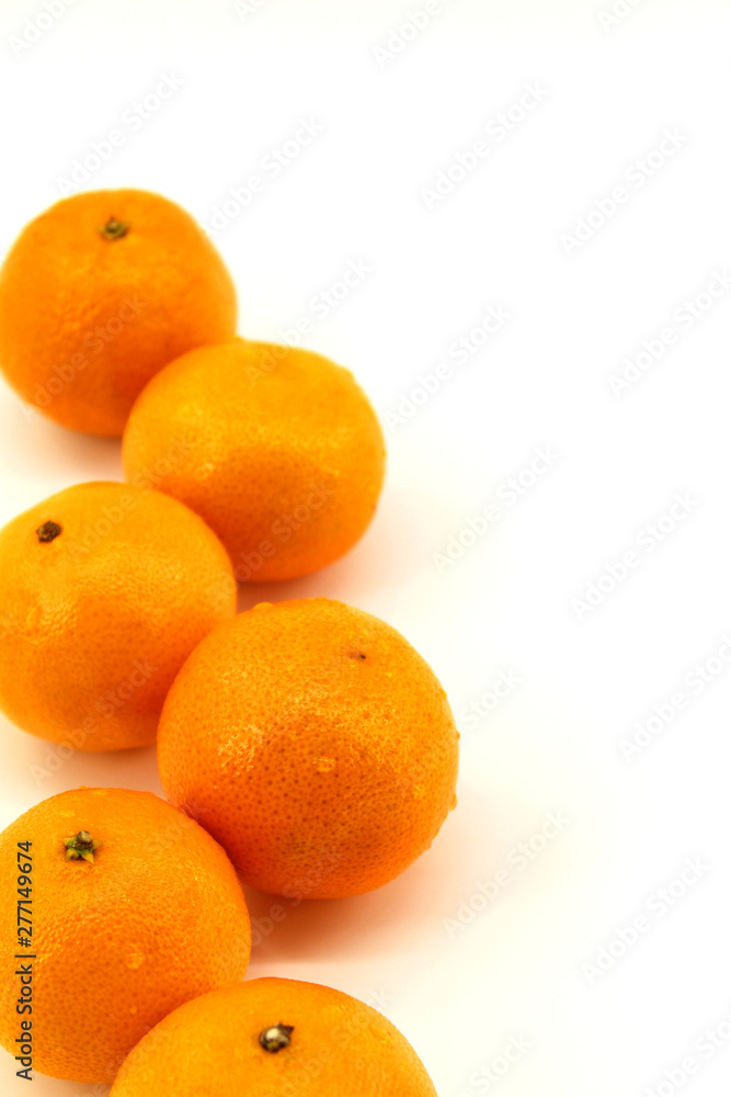 Vertical photo, white background, fresh tangerines in a row, six pieces, lie on the side of the photo Vertical photo, white background, fresh tangerines in a row, six pieces, lie on the side of the photo