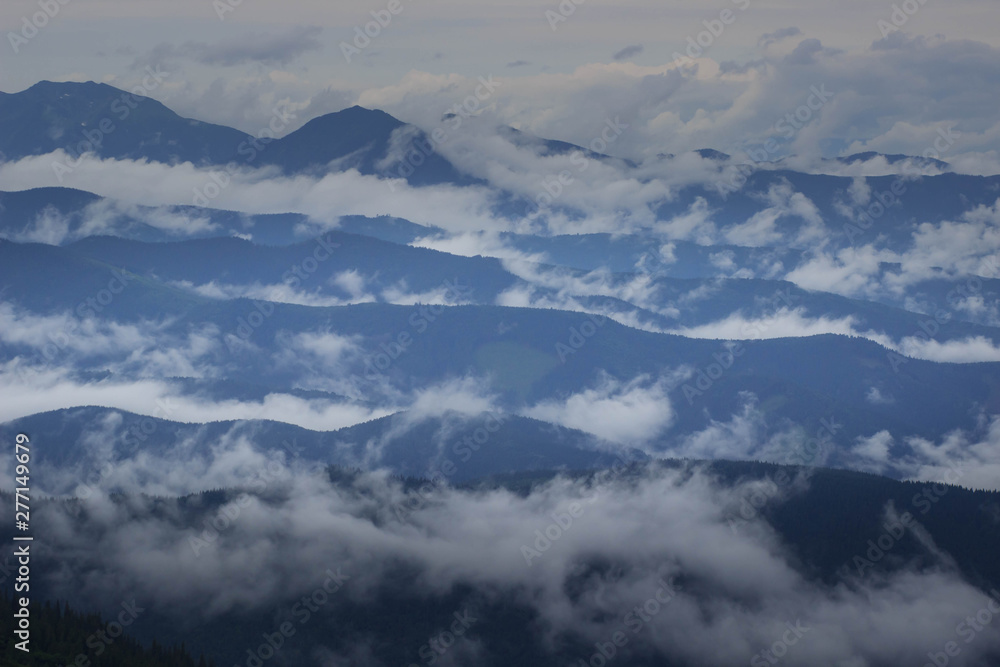 Mountain range with visible silhouettes through the morning colorful fog.