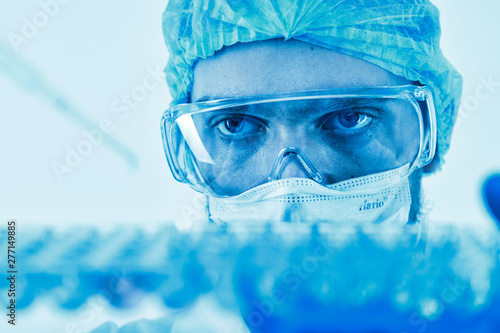 Scientist dropping liquid with pipette into cells photo