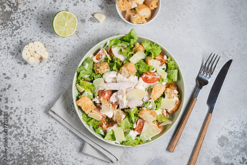 Caesar salad with chicken, Parmesan and wheat croutons on a vintage grey background. Light diet dinner.