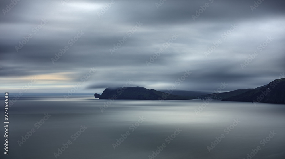 Fototapeta premium Sorvagsvatn lake cliffs backlit long exposure in the horizon at sunset, Faroe Islands
