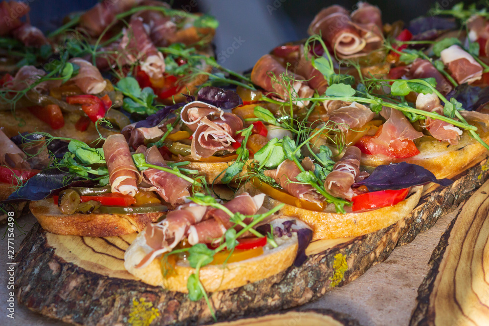 Fototapeta premium Close up bruschetta with proschuto, tomato, parmesan cheese and arugula