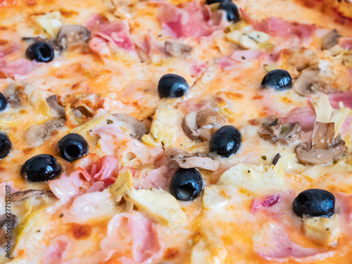 Close up of an Italian pizza with olives, ham, mushrooms and cheese.