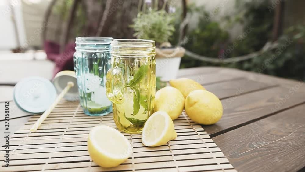 Homemade fresh lemonade with mint and ice. Making two lemon cocktail, lifestyle. Outdoor shot in summertime. 60 fps. Homemade fresh lemonade with mint and ice. Making two lemon cocktail, lifestyle. Outdoor shot in summertime. 60 fps.