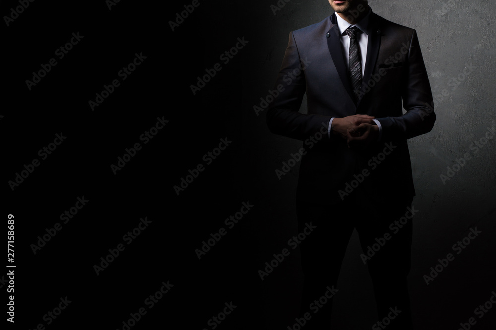 Young handsome successful business man in a suit. Isolated on dark background, copy space. Young handsome successful business man in a suit. Isolated on dark background, copy space.