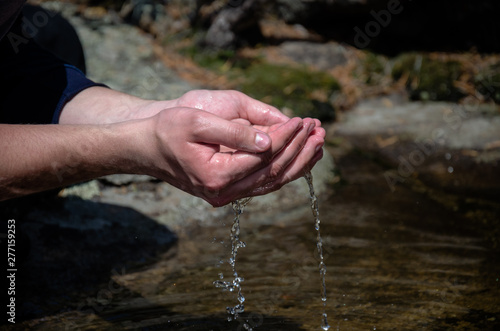 Beautiful hands on a wild brook. Stream of clean water pouring into hands © Kirill