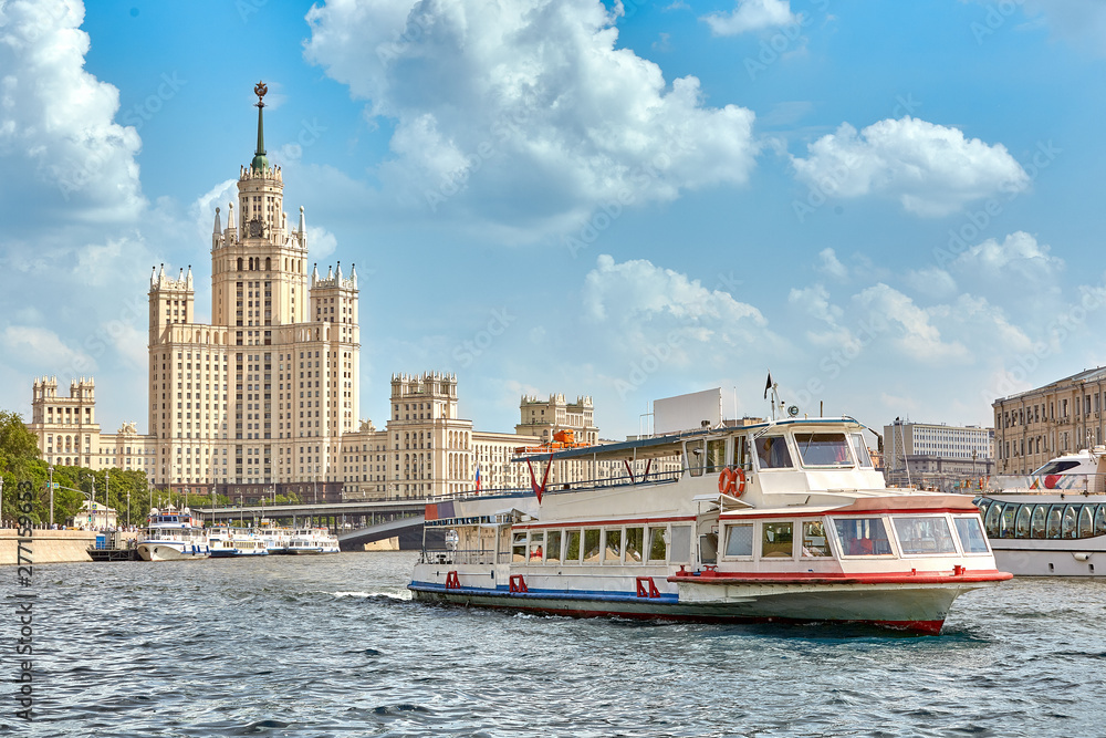 Fototapeta premium Modern river ship on the river in the city, near shopping centers and modern skyscrapers. The ship is moored in a picturesque modern urban architecture. Tourism, rest in the city, river transport.