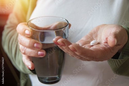 senior hand with pills and glass of water