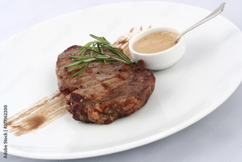Meat medallions with fresh arugula. Close-up on a white plate Meat medallions with fresh arugula. Close-up on a white plate