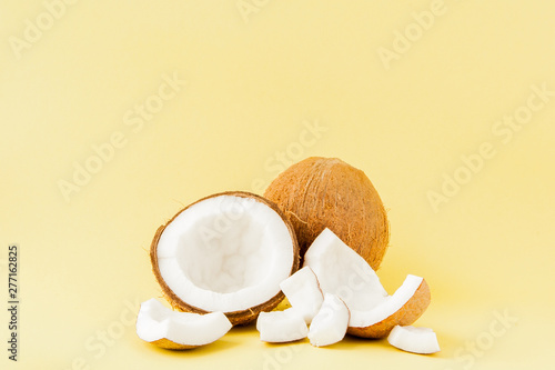 close up fresh coconut pieces isolated on a yellow background, tropical fruit concept, flat lay, pop art, copy space
