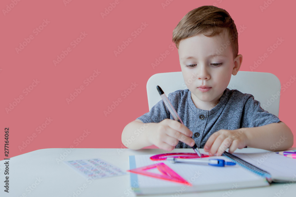 Portrait of cute kid boy at home making homework. Little concentrated child writing with colorful pencil, indoors. Elementary school and education. Kid learning writing letters and numbers Portrait of cute kid boy at home making homework. Little concentrated child writing with colorful pencil, indoors. Elementary school and education. Kid learning writing letters and numbers