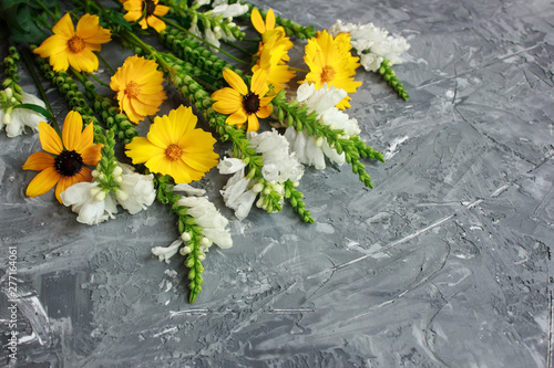 Beautiful yellow and white summer wild flowers on gray concrete background