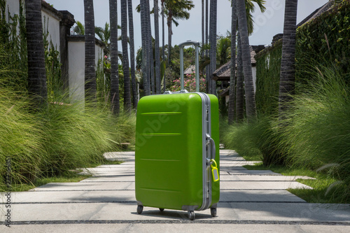 Green luggage in the tropical resort, arriving on the summer vacation destination, no people