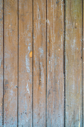 old painted wooden planks of yellow color are peeling off from time. Paint peeling off the wooden surface of the old planks. Texture of old painted wooden boards
