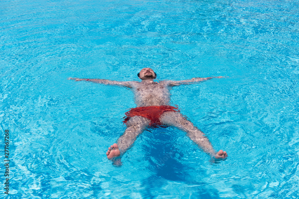 A young man swims in the pool, arms outstretched